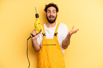 young man feeling extremely shocked and surprised. handyman with a drill