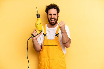 young man shouting aggressively with an angry expression. handyman with a drill