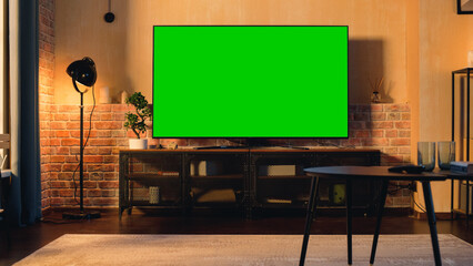 Stylish Loft Apartment Interior with TV Set with Green Screen Mock Up Display Standing on...