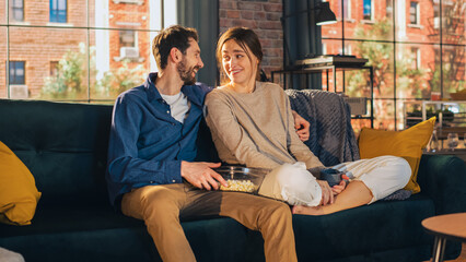 Portrait of Young Couple Spending Time at Home, Sitting on a Sofa, Man Embracing His Girlfriend...