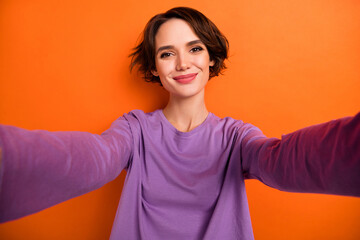 Photo of funny dreamy girl dressed purple pullover recording self video smiling isolated orange color background
