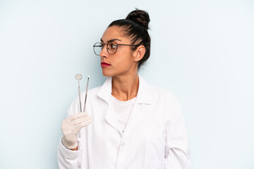 hispanic woman on profile view thinking, imagining or daydreaming. dentist concept
