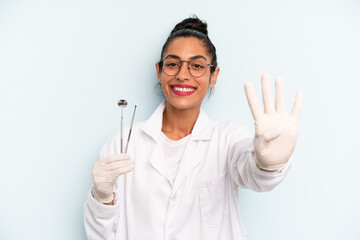 hispanic woman smiling and looking friendly, showing number four. dentist concept
