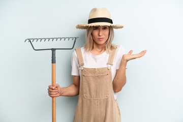 blonde woman feeling puzzled and confused and doubting. farmer and rake cocnept