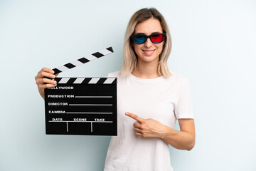 blonde woman smiling cheerfully, feeling happy and pointing to the side. film or movie concept