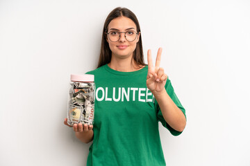 pretty woman smiling and looking friendly, showing number two. volunteer and donation concept
