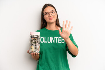 pretty woman smiling and looking friendly, showing number five. volunteer and donation concept