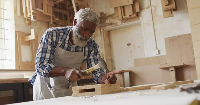 African american male carpenter hammering nails into the wood at a carpentry shop