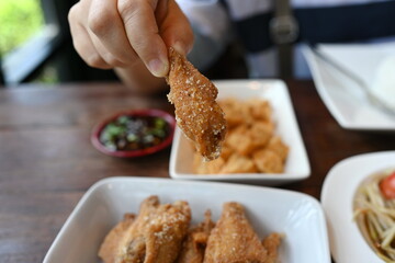 Woman's hand holding salted fried chicken wings Crispy battered chicken fried in oil sprinkled with salt and spices is an appetizer often served with papaya salad or spicy dipping sauce.  popular food