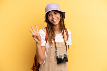 pretty woman smiling and looking friendly, showing number three. tourist photographer concept