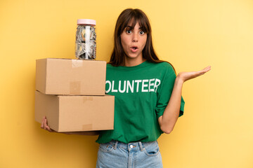 pretty woman looking surprised and shocked, with jaw dropped holding an object. volunteer and...