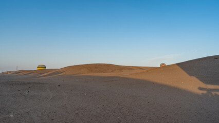 Balloons rise above the sand dunes of the desert. Shadows on the sand. Tire tracks are visible. Clear blue sky. Copy space. Egypt. Luxor