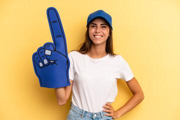 hispanic woman smiling happily with a hand on hip and confident. number one fan concept