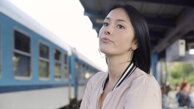 A young beautiful Caucasian woman is frustrated as she misses a train and watches it leave without her at a train station - closeup