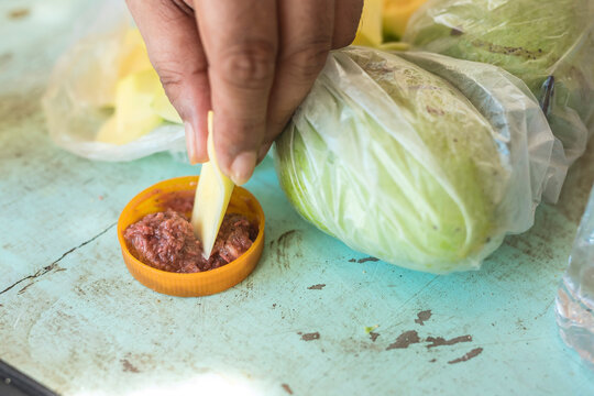 A man dips a slice of green mango into bagoong, a condiment made with fermented fish, krill or shrimp paste.