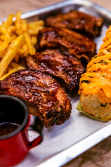 succulent and smoked grilled  pork ribs with corn cob and french fries with barbecue sauce on the side