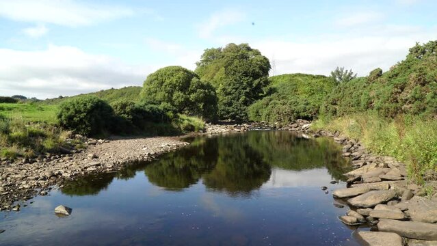 Scenic view of a slow flowing river surrounded by greenery in Dunbeath Strath, Scottish Highlands