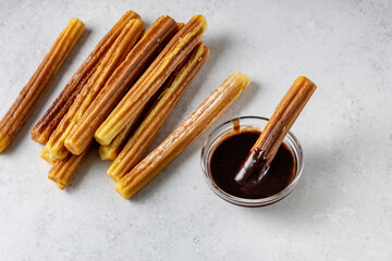 traditional Spanish pastries - churros and chocolate sauce on a gray background, top view