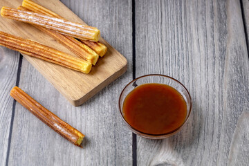 traditional Spanish pastries - churros and chocolate sauce on a wooden background, top view
