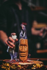 Vertical shot of a burning cocktail in a tiki cup in the background of a bardender.