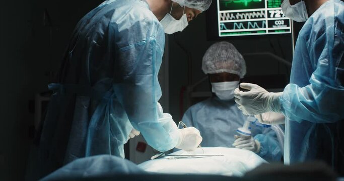 A team of surgeons perform an operation in a bright operating room
