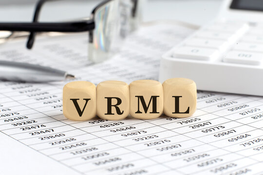 wooden cubes with the word VRML - Virtual Reality Markup Language on a financial background with chart, calculator, pen and glasses, business concept.