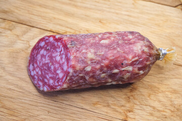 Half a stick of smoked sausage on a wooden surface. A close-up picture of food. Sausage on a wooden cutting board.