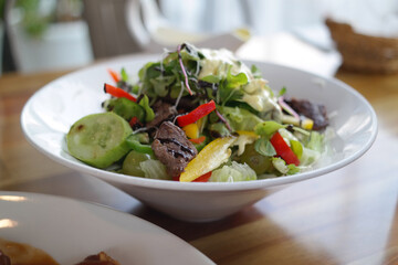 Salad is served on a white round plate.