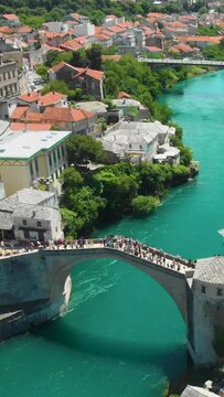Vertical aerial footage of the crowded Mostar Bridge (Stari Most) in Mostar, Bosnia and Herzegovina