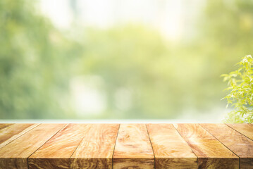 Selective focus.Empty wood table top on beautiful background of blur garden in the morning.