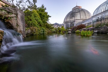 Waterfall and lake in long exposure with Anna Scripps Whitcomb Conservatory in the background.