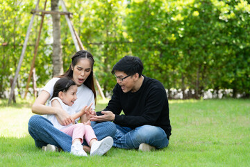 Naklejka premium Asian family with both father, mother and daughter having fun in the garden of the house happily