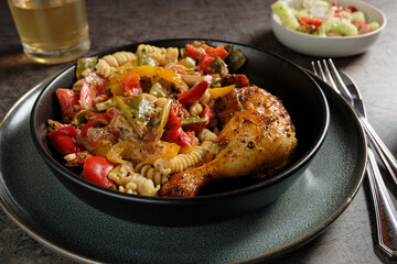 Braised chicken leg with spiral noodles and roasted vegetables.