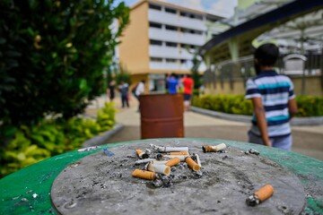 Cigarette butts outdoors in the park with walking people in the background