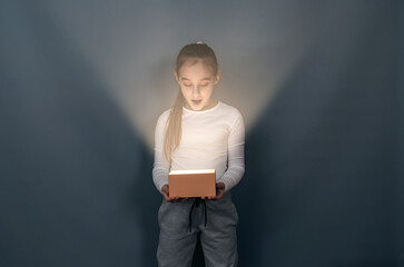 Shocked surprised child with glowing box. An interesting surprise. Gift.