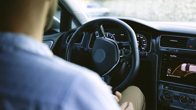 Unrecognizable person's hands holding steering wheel while driving modern electric car on the street road. Confident man driving expensive car. Driver Turning Steering Wheel In Luxurious Auto On Trip