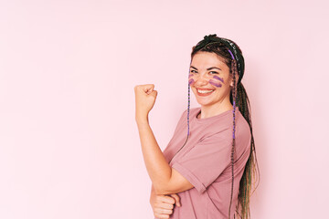Laughing girl with purple paint on her face clenching her fist against a pink background.