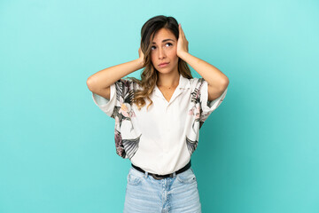 Young woman over isolated blue background frustrated and covering ears