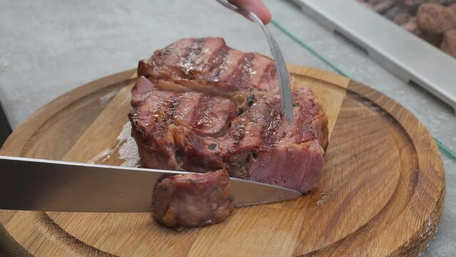 Cutting, slicing medium rare meat grilled barbecue steak with knife