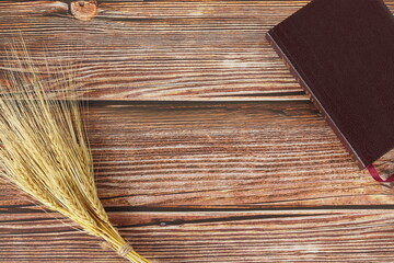 Ripe gold barley sheaf and closed Holy Bible book on wooden table with copy space. Top view....