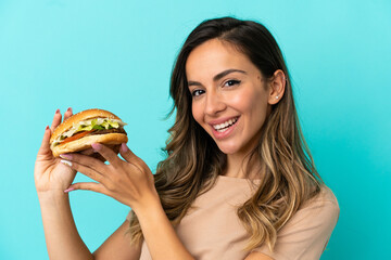 Young woman holding a burger over isolated background
