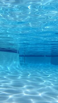 Vertical video of empty suburban swimming pool with underwater sunlight patterns.