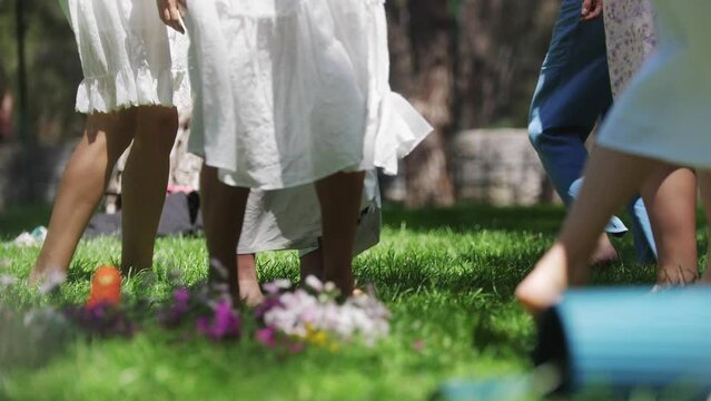 Women in traditional clothing dancing on the grass with bare feet during folk festival