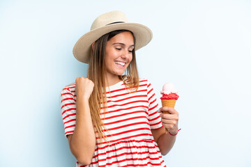 Young caucasian woman holding an ice cream isolated on blue background celebrating a victory