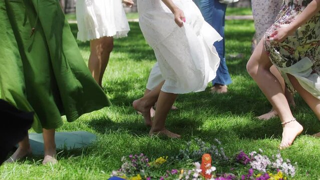 Women in light dresses dancing on the grass with bare feet during folk festival