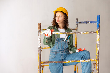 Young woman, professional builder makes room repairs using different work tools. Gender equality....