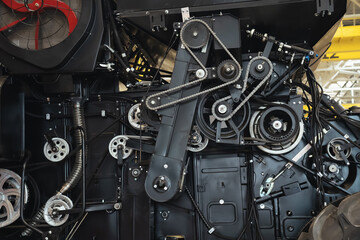 Close-up of combine harvester mechanisms with iron chains, power units and hydraulic systems. Agricultural machinery in process of production and assembly.