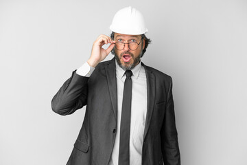 Young architect man with helmet over isolated background with glasses and surprised