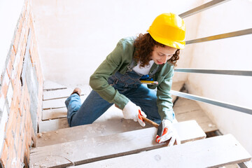 Young woman, professional builder makes room repairs using different work tools. Gender equality....