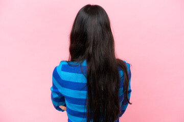 Young Colombian woman isolated on pink background in back position